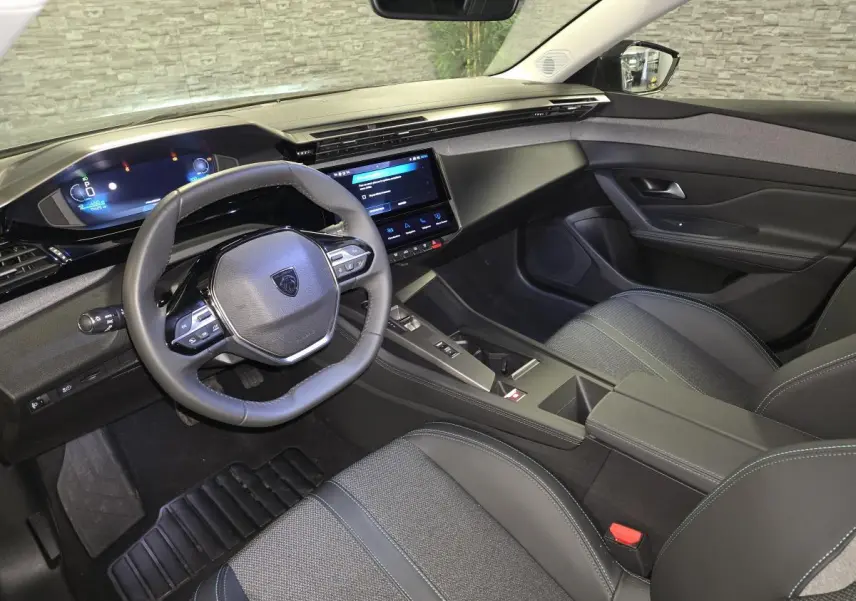 Intérieur avant droit du Peugeot 408 électrique 2024, volant compact, écran tactile 10 pouces et sellerie tri-matières noire.