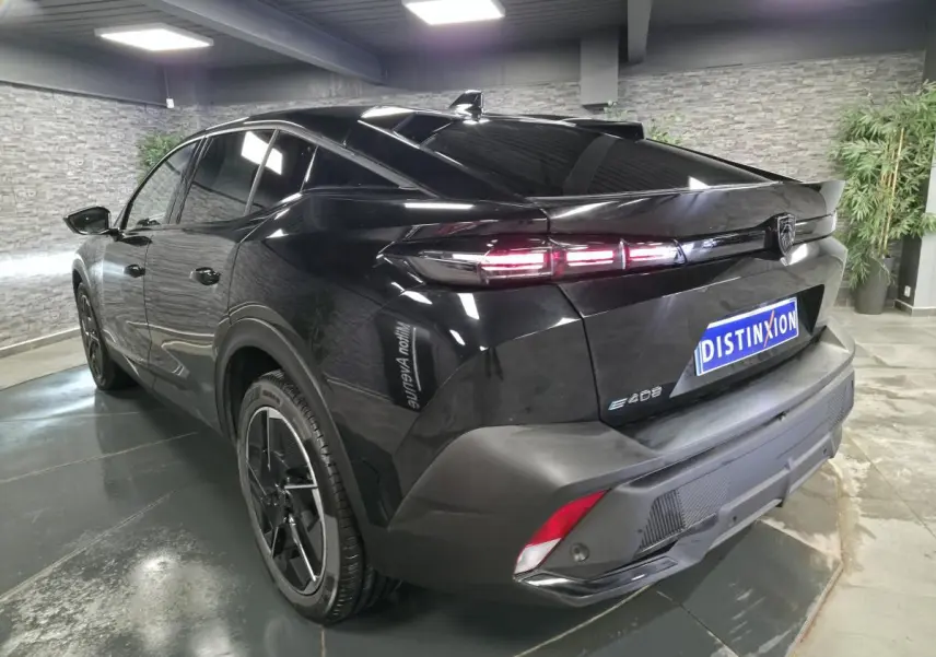 Vue 3/4 arrière droite d’une Peugeot 408 électrique noire Perla Nera avec feux arrière LED et jantes alliage 19 pouces.