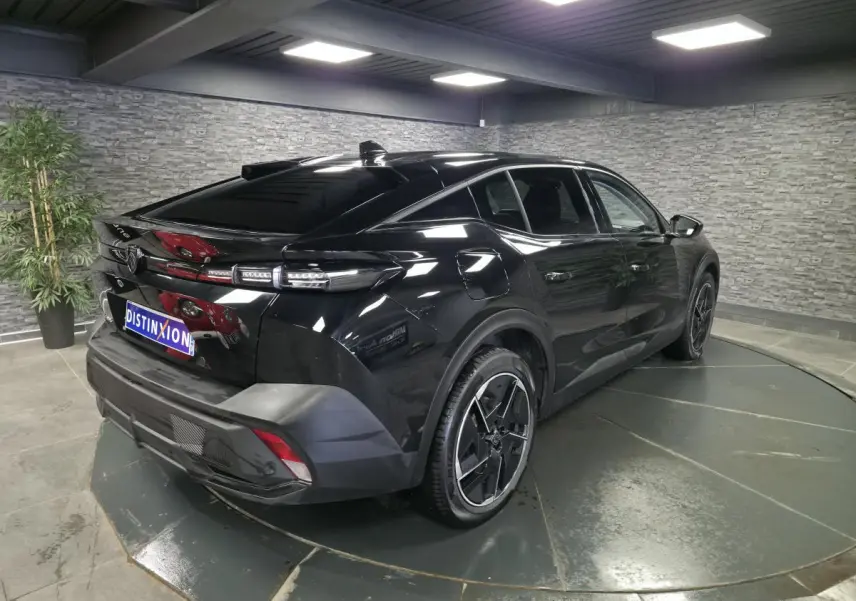 Peugeot 408 électrique noire vue 3/4 arrière droit dans un showroom avec jantes alliage 19 pouces diamantées.