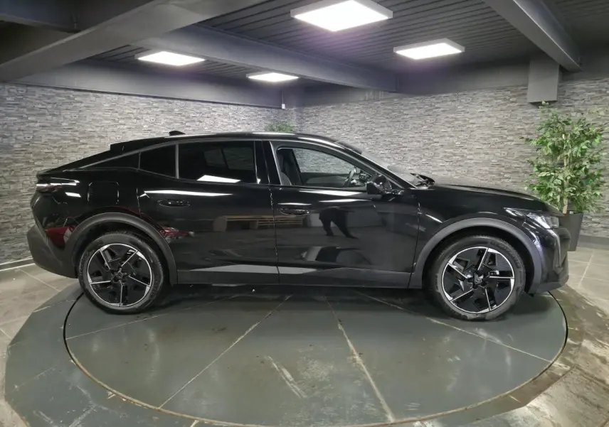 Vue de profil côté gauche d’une Peugeot 408 électrique noire Perla Nera avec jantes alliage 19 pouces diamantées.