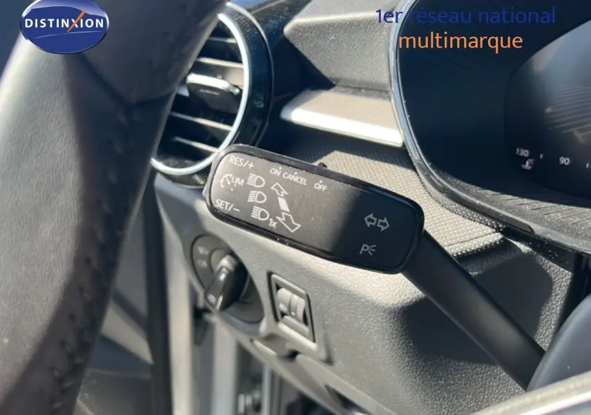 Gros plan sur la commande de régulateur de vitesse à gauche du volant dans l’habitacle gris noir d’une Skoda Fabia Reflex Silver.
