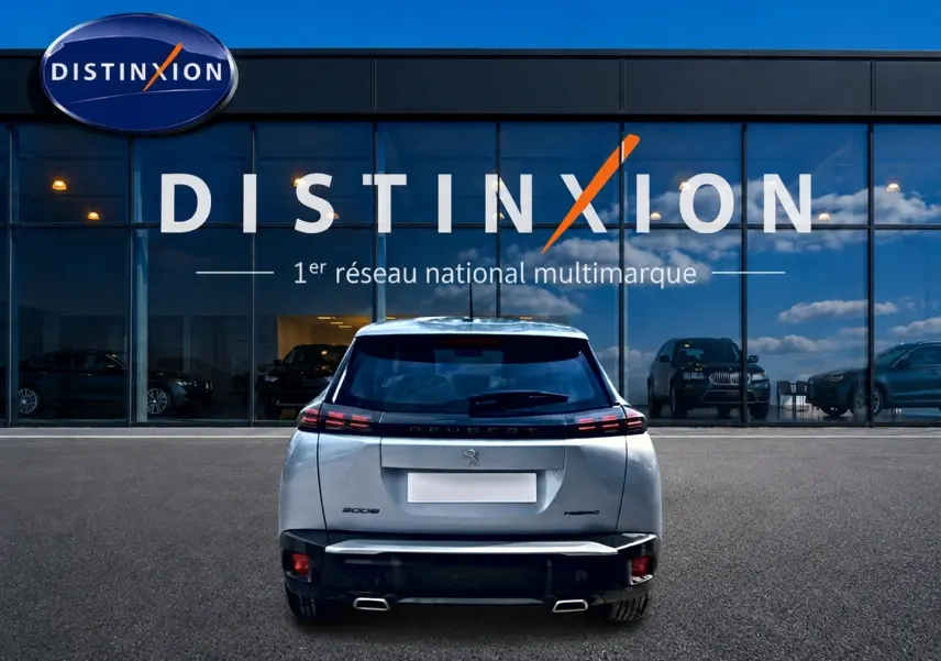 Vue arrière d’un Peugeot 2008 gris 2025 avec feux arrière LED et double sortie d’échappement, devant une vitrine Distinxion.