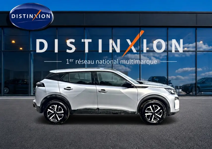 Peugeot 2008 gris en profil droit, soulignant ses jantes noires et détails noirs contrastants, devant une vitrine Distinxion.