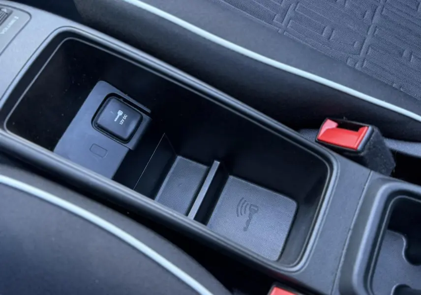 Vue rapprochée de la console centrale noire de la Fiat 500 Cabriolet électrique, montrant un port 12V et un espace de rangement.