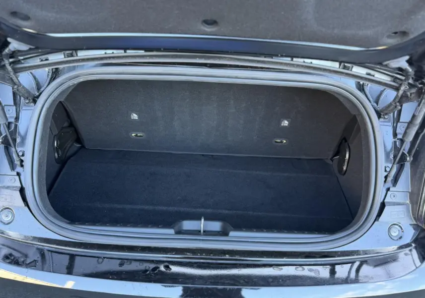 Coffre ouvert vu de dessus de la Fiat 500 Cabriolet électrique noire, montrant un espace de rangement vide et propre.