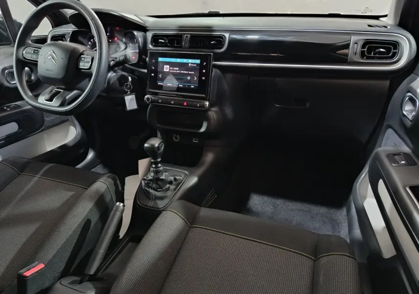 Vue intérieure côté conducteur de la Citroën C3 2024 gris foncé, avec tableau de bord central tactile et volant multifonctions.