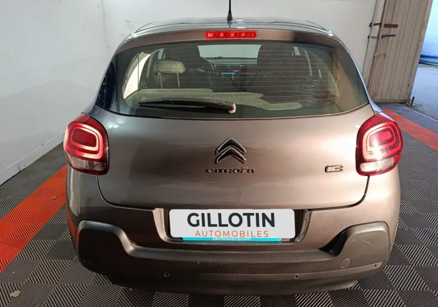 Vue arrière d'une Citroën C3 gris foncé 2024 avec feux LED allumés et logo visible sur un sol à damier noir et orange.