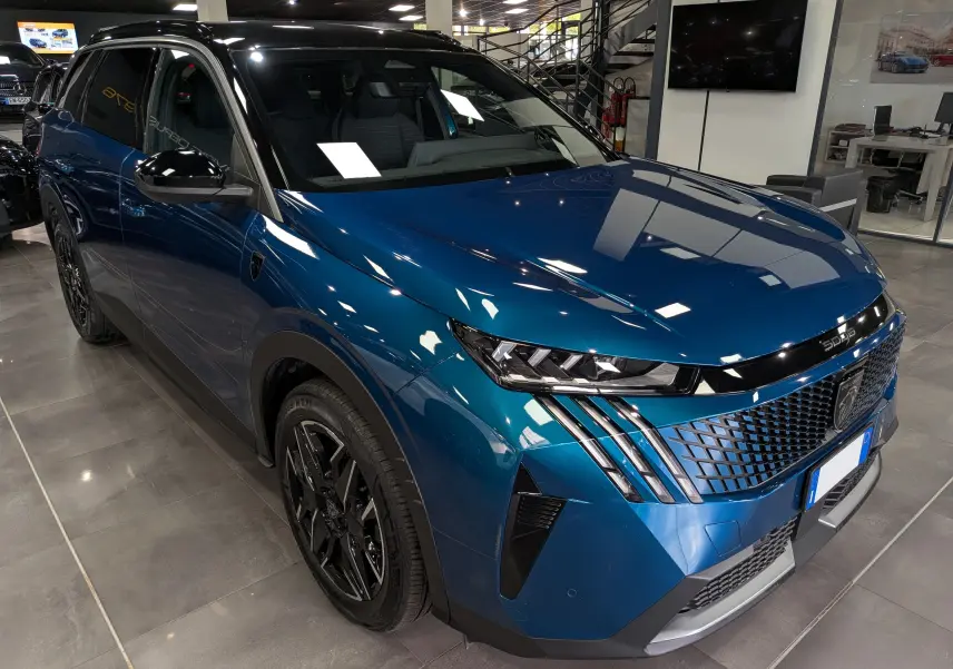 Vue 3/4 avant droit du Peugeot 5008 Hybrid bleu Obsession avec toit noir et jantes noires en concession.