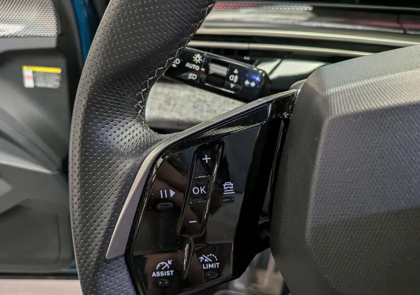 Gros plan sur les commandes au volant en cuir perforé noir du Peugeot 5008 Hybrid 145 CH e-DCS6 GT 2025.