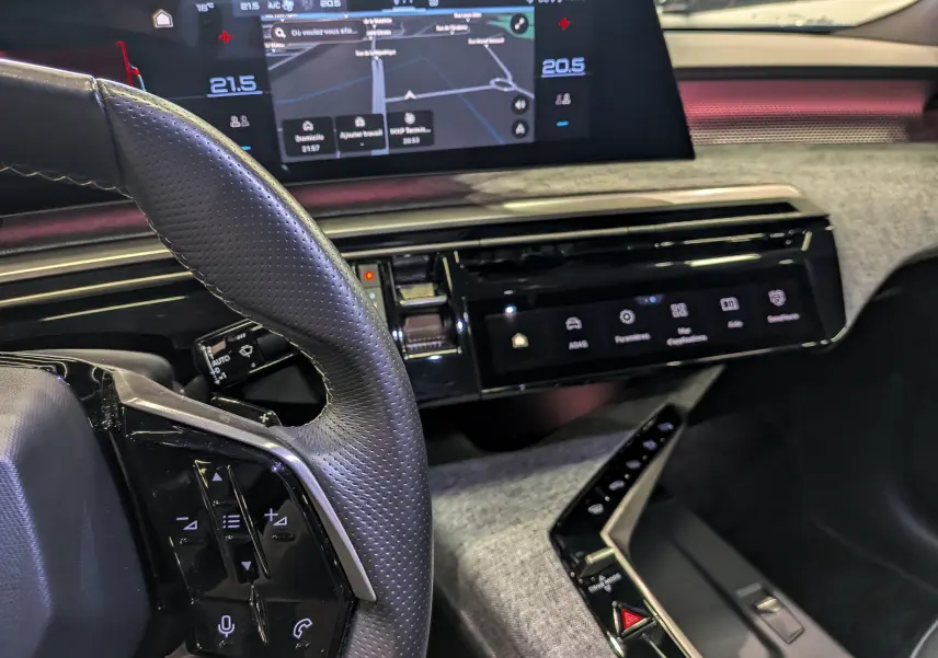 Vue rapprochée de l’intérieur du Peugeot 5008 Hybrid 145 GT 2025, montrant le volant, l’écran tactile et la console centrale.