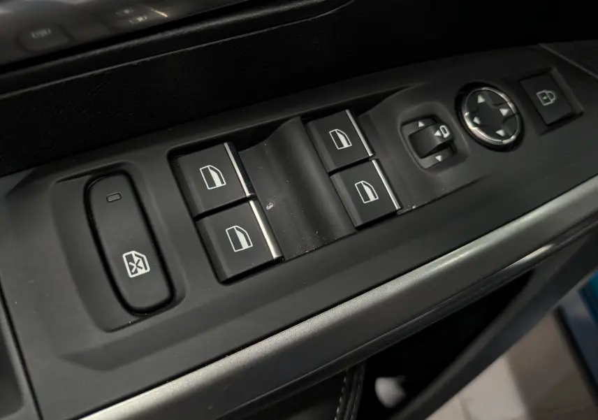 Gros plan sur les commandes des vitres et rétroviseurs côté gauche de la Peugeot 5008 Hybrid 2025, intérieur noir.