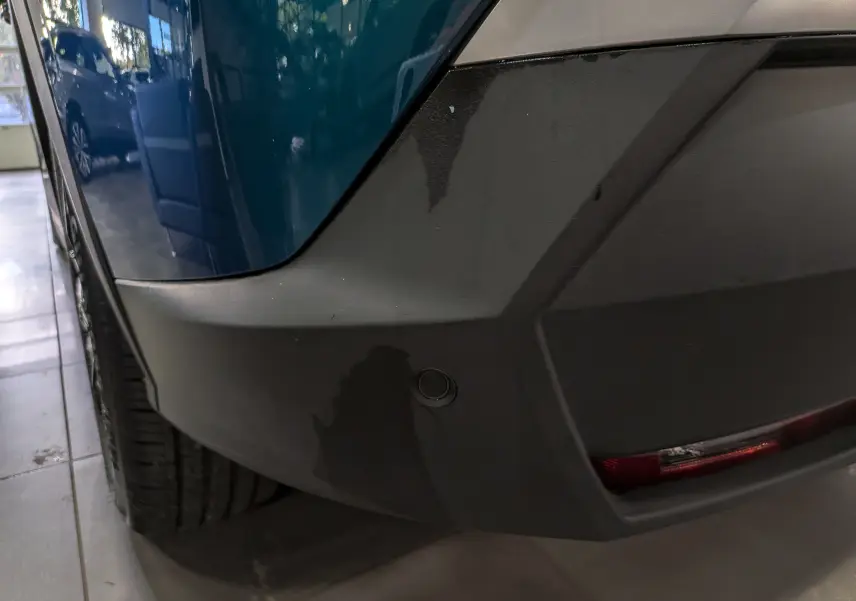 Gros plan sur le pare-chocs arrière gauche bleu Obsession du Peugeot 5008 Hybrid 145 CH e-DCS6 GT avec toit noir.