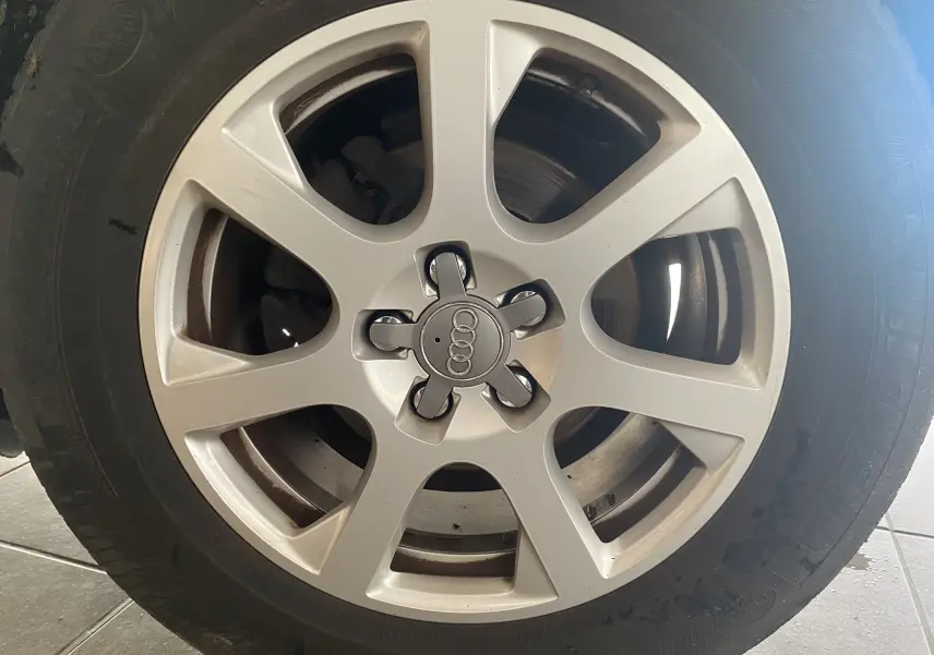 Gros plan sur la jante alliage argentée avec logo Audi au centre d'un pneu monté sur un Audi Q5 blanc.