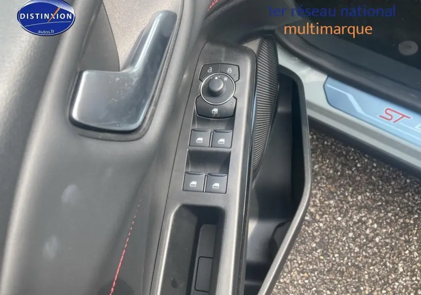 Gros plan sur la commande des vitres côté conducteur du Ford Puma gris cactus avec surpiqûres rouges ST visible sur le seuil de porte.