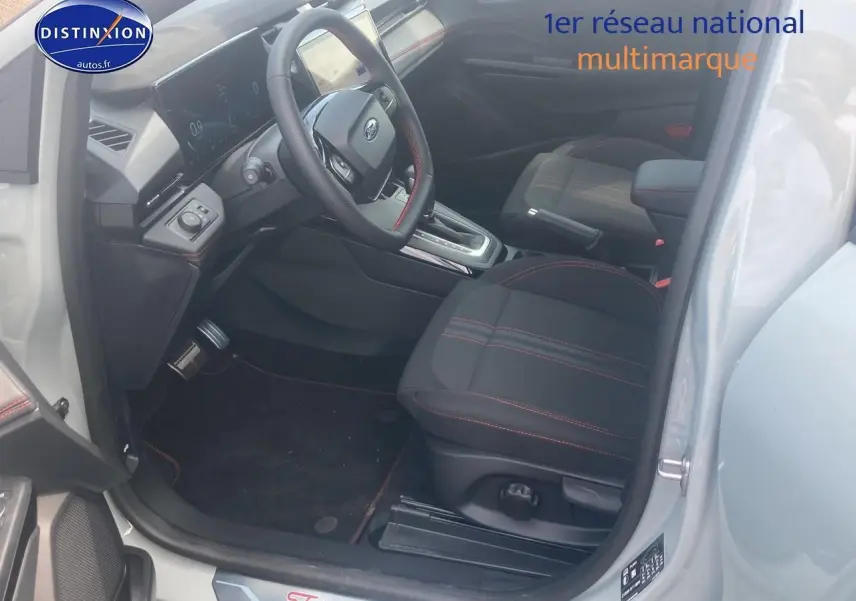 Intérieur avant droit du Ford Puma gris cactus 2025, sièges tissu noir avec surpiqûres rouges et volant multifonction.