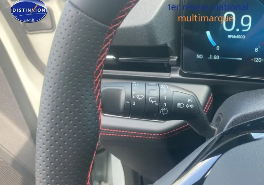 Gros plan sur la commande d’essuie-glace et volant perforé avec surpiqûres rouges du Ford Puma gris cactus 2025.