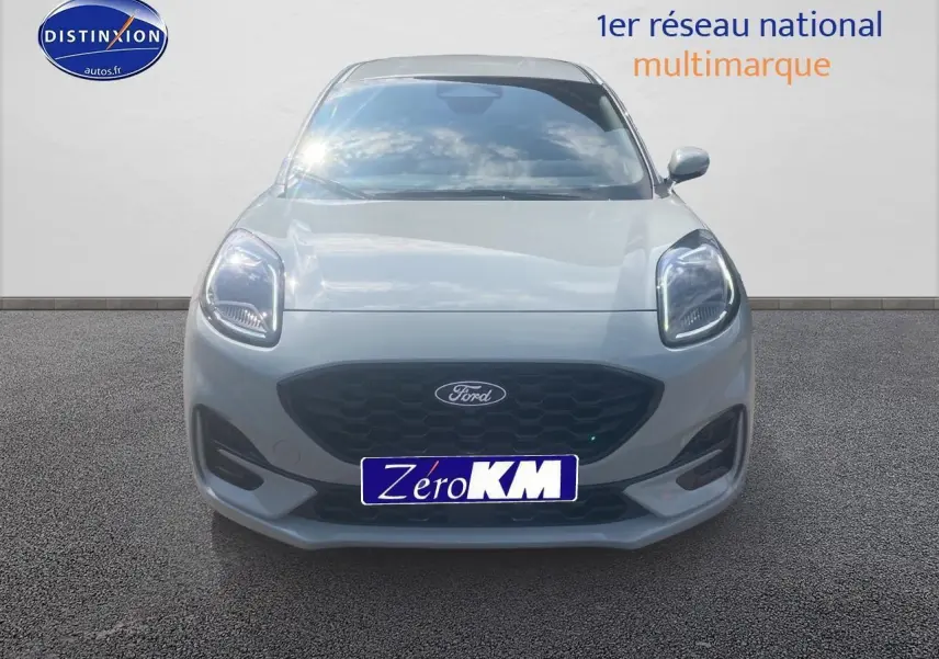 Vue frontale d'un Ford Puma 2025 gris cactus avec calandre noire et phares LED allumés sur fond neutre.
