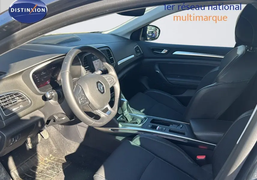 Vue intérieure côté conducteur de la Renault Mégane Break gris titanium, avec tableau de bord et sièges noirs en cuir.