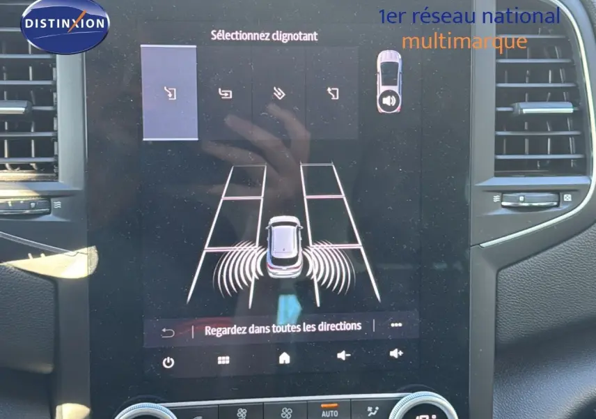 Écran tactile intérieur montrant l’aide au stationnement d’une Renault Mégane Break gris titanium, vue de face.