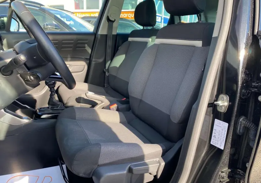 Vue intérieure côté conducteur du Citroën C3 Aircross noir 2023, montrant siège tissu bicolore et volant cuir.