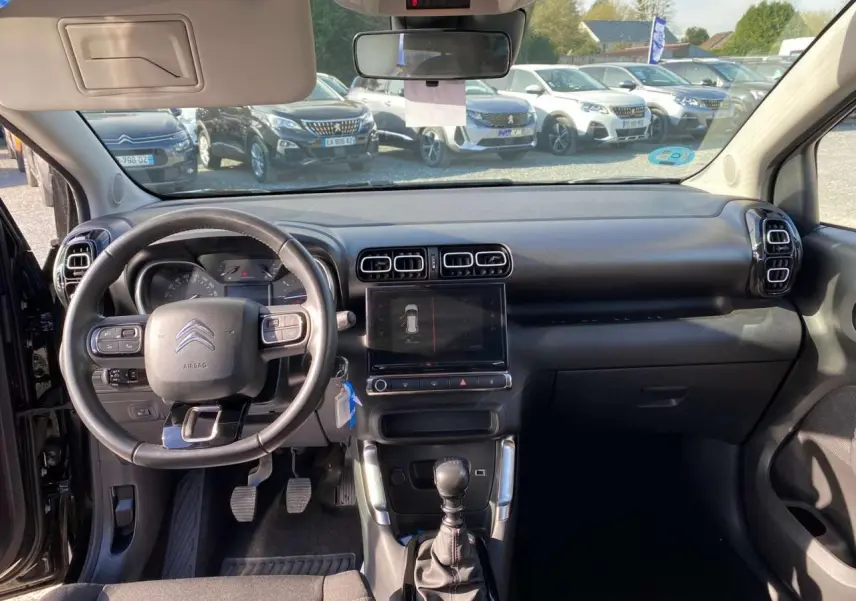 Vue intérieure avant du Citroën C3 Aircross noir 2023, volant cuir, écran tactile et levier de vitesse manuel visibles.