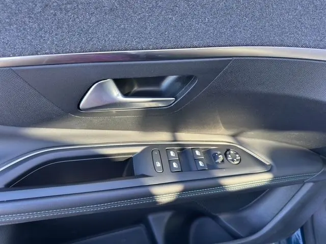 Gros plan sur la poignée intérieure et les commandes de fenêtre côté conducteur d'une Peugeot 3008 bleu Celebes 2023.