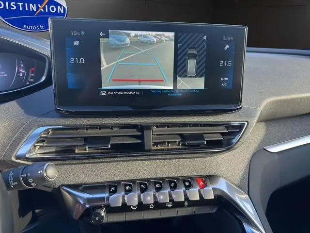 Vue du tableau de bord du Peugeot 3008 bleu Celebes 2023, avec écran multimédia affichant la caméra de recul et commandes centrales visibles.