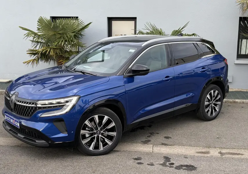 Vue 3/4 avant droit du Renault Austral E-Tech hybride bleu Iron avec toit panoramique noir et jantes alliage 19 pouces.