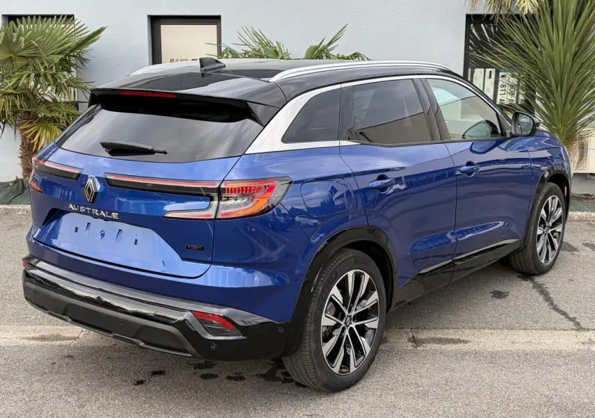 Vue 3/4 arrière droite du Renault Austral bleu Iron avec toit noir panoramique et jantes alliage noires.