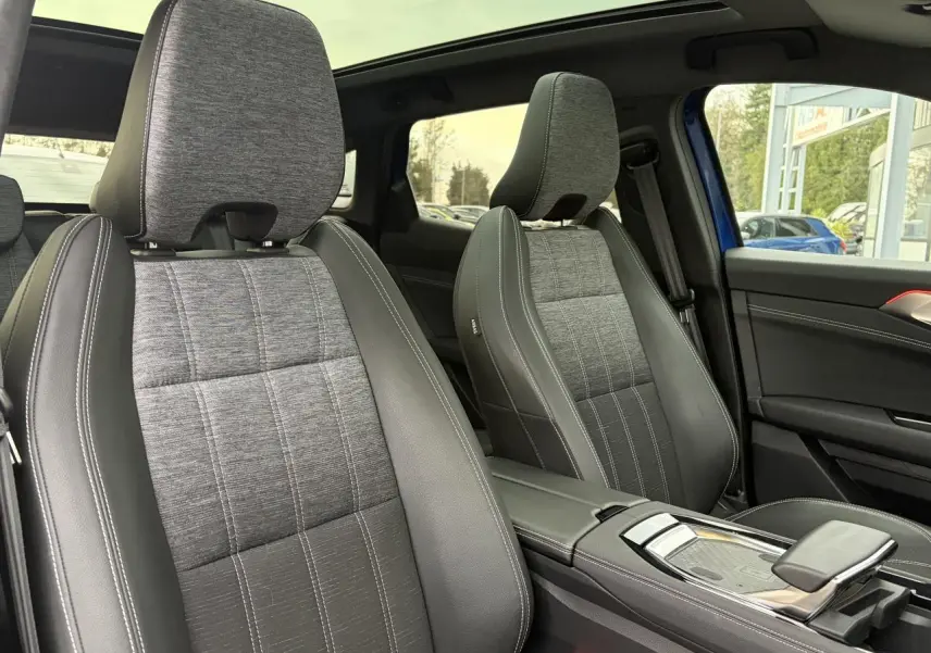 Vue intérieure des sièges avant gris tissu et cuir noir du Renault Austral E-Tech 2025 avec toit panoramique visible.