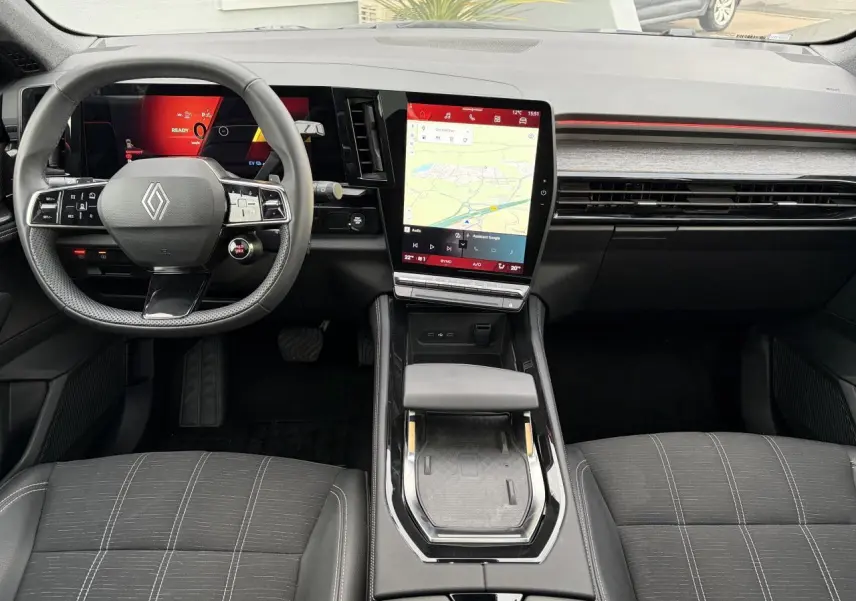 Vue intérieure avant du Renault Austral E-Tech 2025, tableau de bord noir avec écran tactile vertical et volant multifonction.