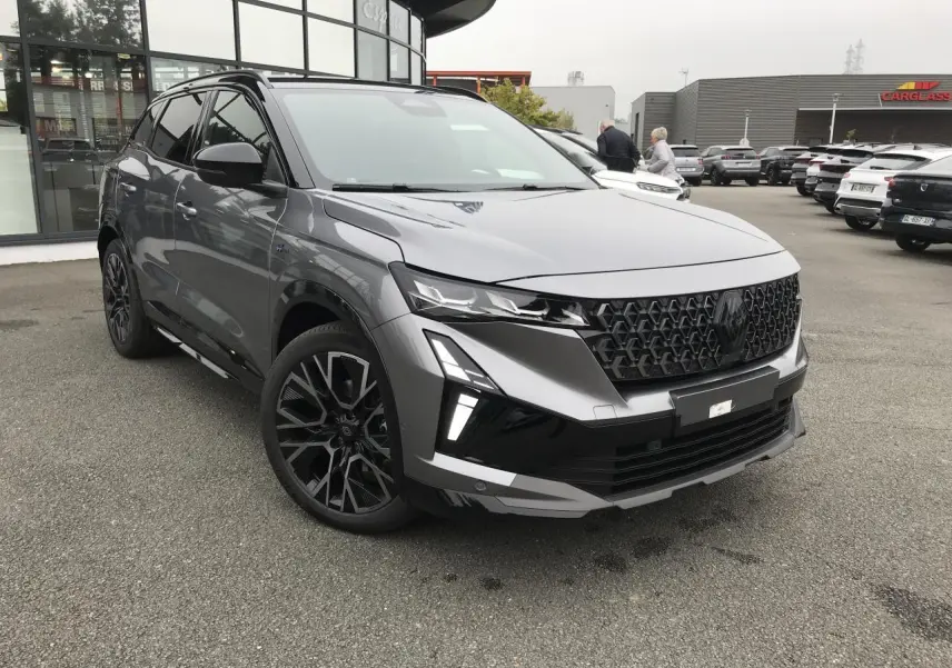 Renault Austral full hybrid gris et noir, vue 3/4 avant avec calandre noire et jantes alliage 20 pouces.