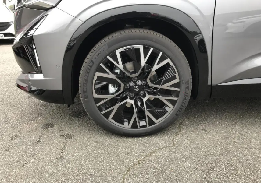 Gros plan sur la roue avant droite du Renault Austral gris bi-ton avec jante alliage 20 pouces noire et grise.