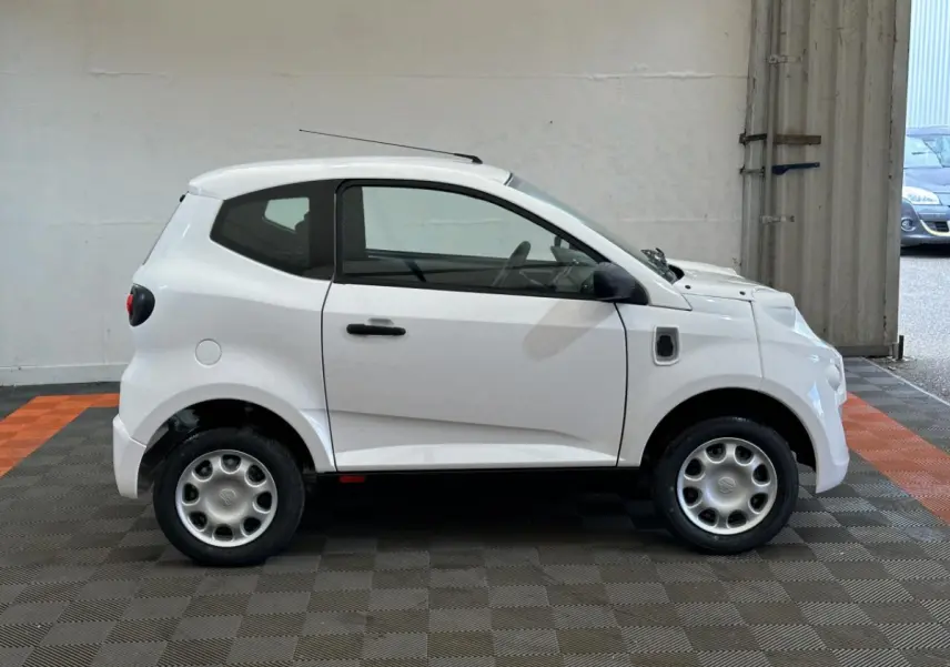 Vue de profil côté droit de l'AIXAM MINAUTO E ACCESS 2026 blanche, petite citadine électrique avec rétroviseur caméra conducteur.