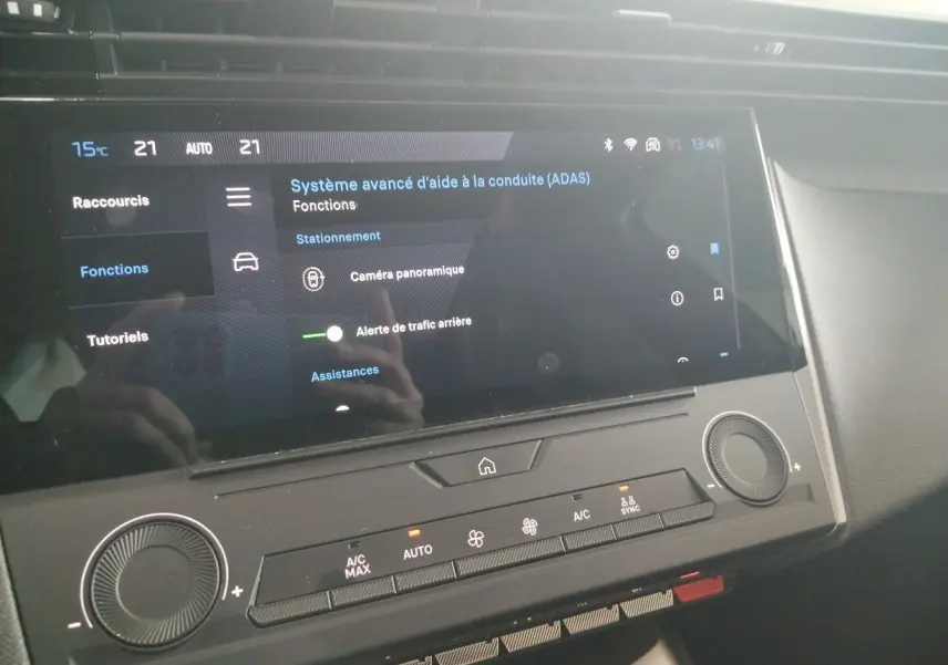 Vue rapprochée de l'écran tactile central et de la console de climatisation d'une Peugeot 308 SW Hybrid gris Artense.