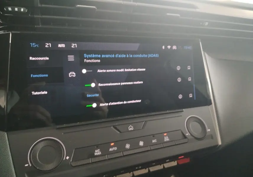 Vue rapprochée de l’écran tactile central du Peugeot 308 SW Hybrid 145 gris Artense, affichant les réglages d’aide à la conduite.