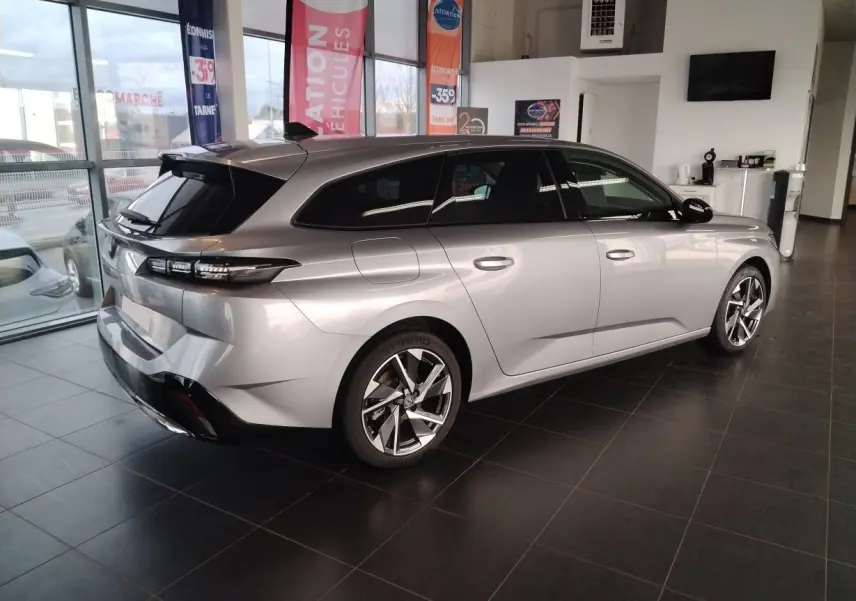 Peugeot 308 SW Hybrid gris Artense vue 3/4 arrière droit en showroom avec jantes alliage et vitres teintées.