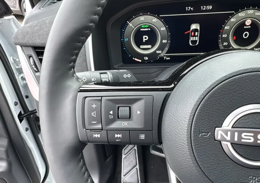 Gros plan sur le volant cuir noir du Nissan Qashqai E-POWER 205 Tekna Plus avec tableau de bord numérique allumé.