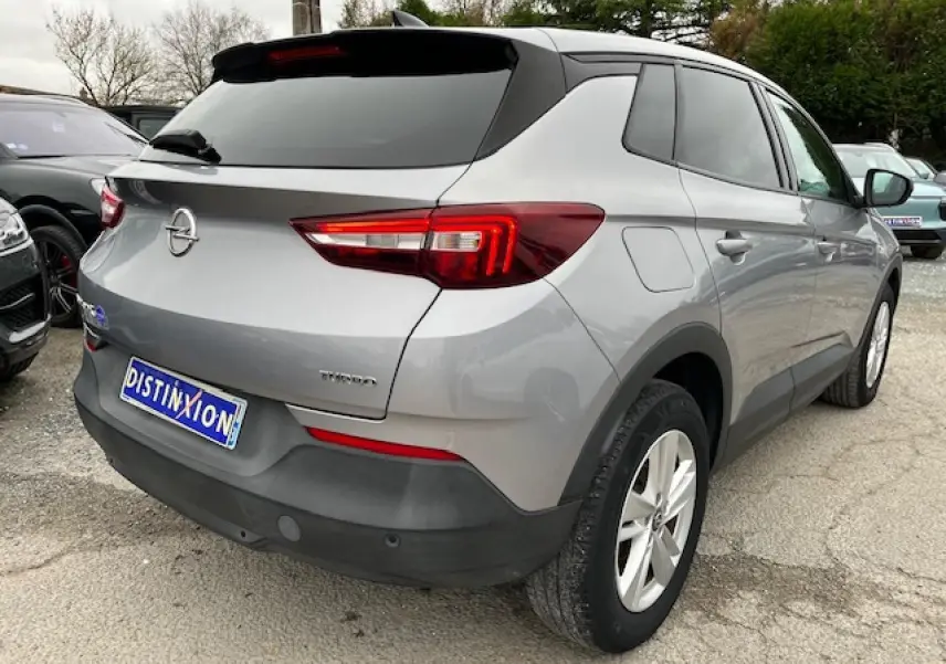 Vue 3/4 arrière droite d'un Opel Grandland X gris 2020 avec feux arrière LED et badge Edition Business visible.