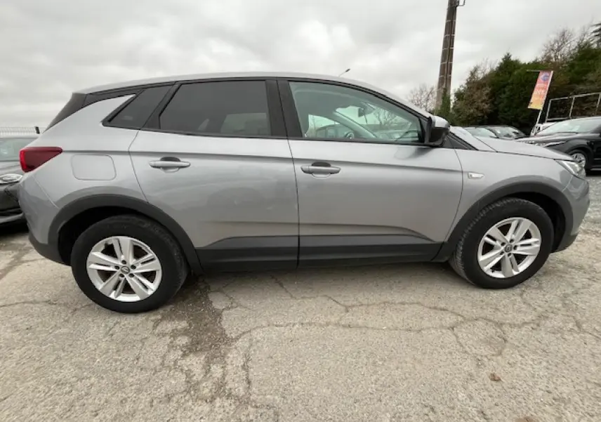 Vue de profil côté gauche d'un Opel Grandland X gris 2020 avec jantes alliage et lignes noires sur les bas de caisse.