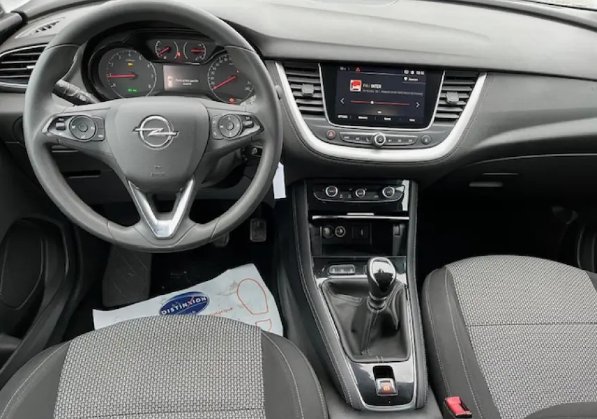 Vue intérieure avant de l'Opel Grandland X 2020 gris, montrant le volant, tableau de bord et levier de vitesses manuel.