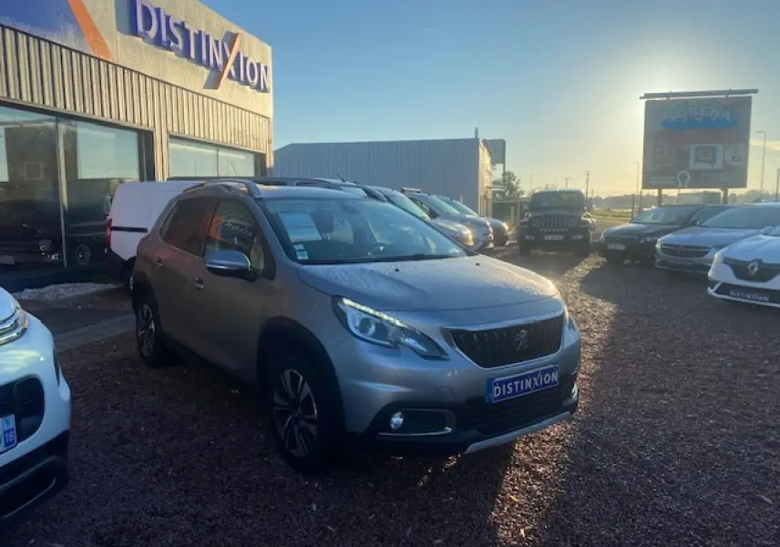 Peugeot 2008 gris Artense vue 3/4 avant droit sur parking avec jantes aluminium et calandre noire distinctive.