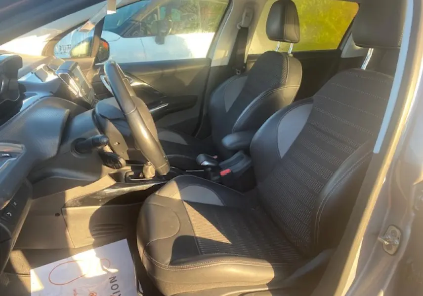 Vue intérieure côté conducteur du Peugeot 2008 gris Artense de 2019, montrant les sièges TEP et tissu, le volant et la console centrale.