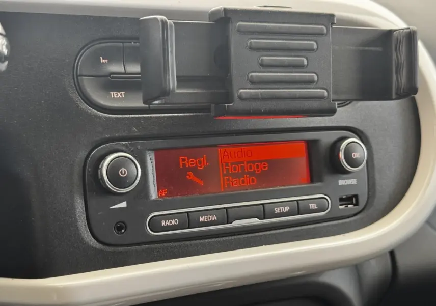Gros plan sur la console centrale noire et beige de la Renault Twingo Intense Energy TCe 90 avec écran radio rouge allumé.