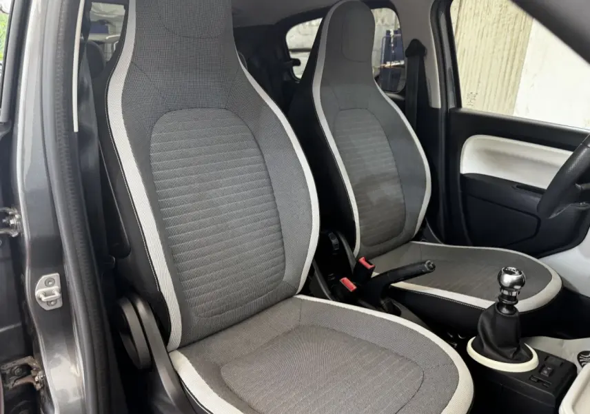 Vue intérieure des sièges avant gris clair et foncé de la Renault Twingo Intense Energy TCe 90 avec levier de vitesse manuel.