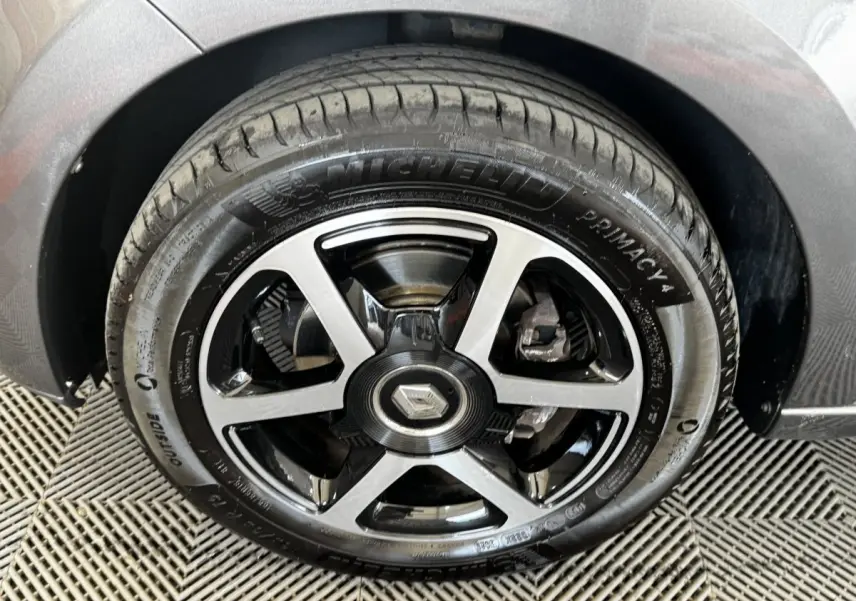 Gros plan sur la roue avant droite d'une Renault Twingo gris foncé, avec jante alliage noire et argentée.