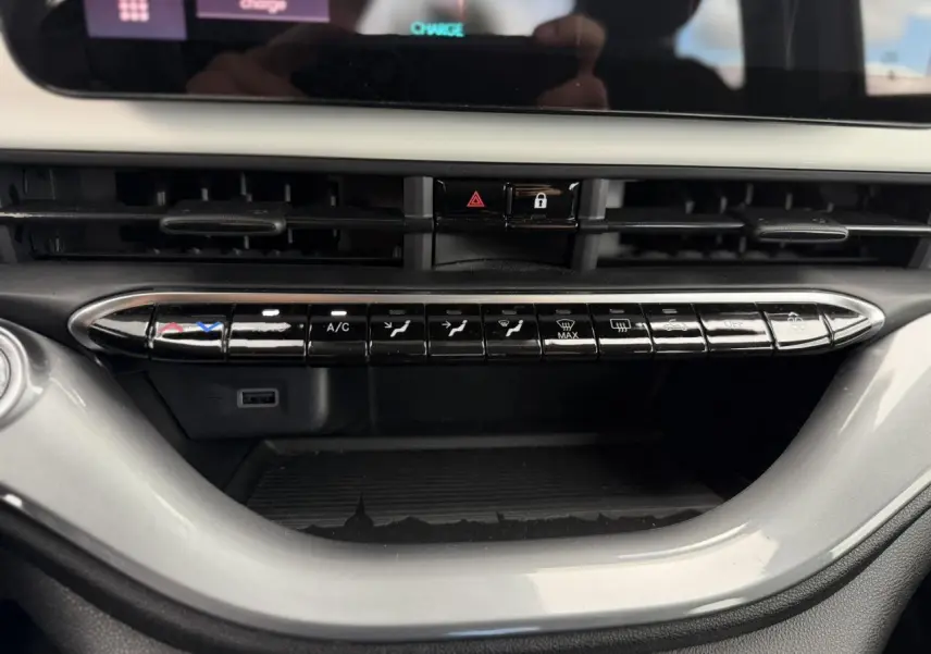 Vue rapprochée de la console centrale du Fiat 500 électrique blanc Arctic, montrant les commandes de climatisation et ventilation.