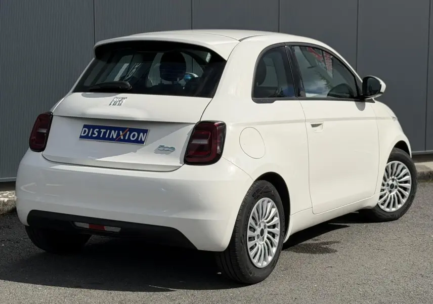 Vue 3/4 arrière droite d'une Fiat 500 électrique blanc Artic avec feux arrière foncés et jantes multibranches.