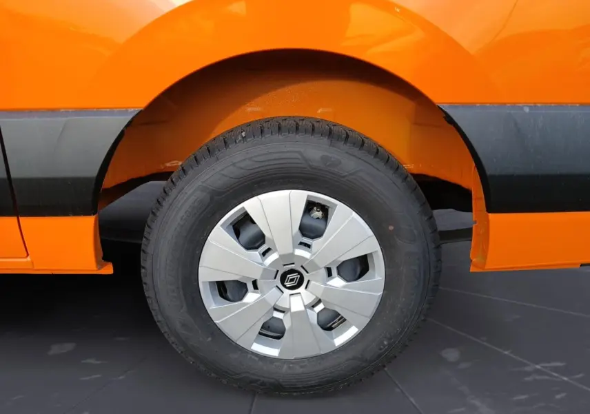 Gros plan sur la roue arrière droite d’un Renault Master orange, avec jante argentée et pneu tous temps visible.
