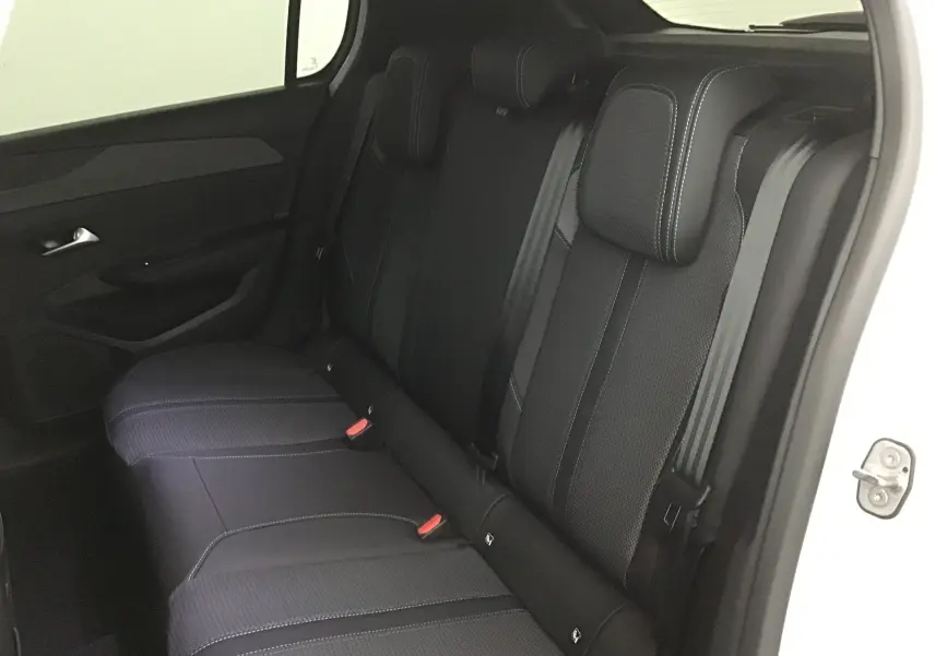 Vue intérieure côté arrière droit du Peugeot 308 2025 blanc Okenite, montrant les sièges arrière noirs avec surpiqûres contrastées.